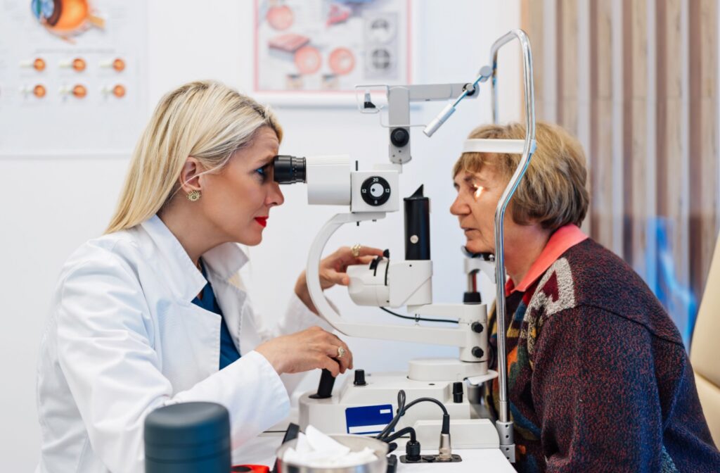 An optometrist carefully examining an older patient's eyes during a dilated eye exam.